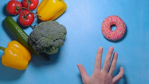 Man don't know what to choose health food or sweet donut Stock Footage 124297487