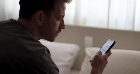 Man doom scrolling through social media or waiting for a message. Alone in Video stock 324843953