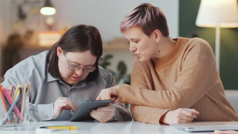 Man with Down Syndrome Using Tablet with Help of Social Worker Stock Footage 148830255