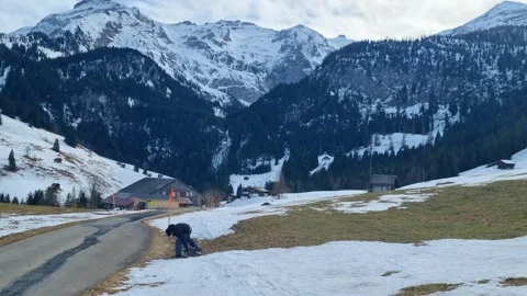 Man drags his sledge over a bare patch in the Swiss mountains, showing the Video stock 304145867