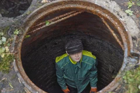 Man in the drain pit. Underground utilities. Stock Photos