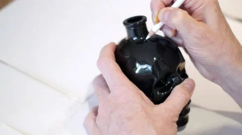 Man drawing on a black skull using white pencil 스톡 동영상 64090977