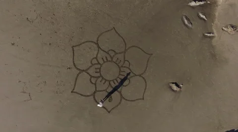 Man drawing a flower design on the beach Stock Footage 58649342