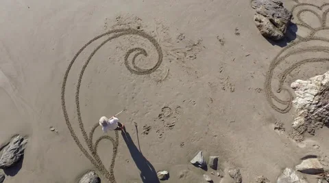 Man drawing a flower mandala design on the beach Stock Footage 58648103