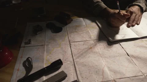 Man drawing map on his rustic table with camping accessories	 Stock Footage 163986102