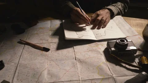Man drawing map on his rustic table with camping accessories	 Stock Footage 163986111