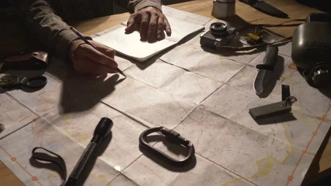 Man drawing map on his rustic table with camping accessories	 Stock Footage 163986119