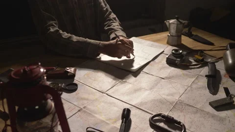 Man drawing map on his rustic table with camping accessories	 Stock Footage 163986135