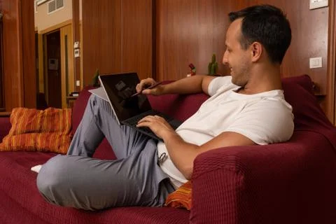 Man drawing in mock up tablet screen laying on the sofa at home Stock Photos