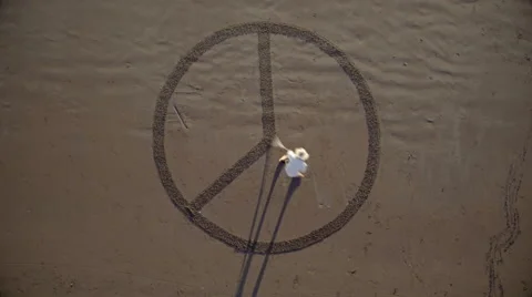 Man drawing the peace symbol in the sand Stock Footage