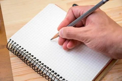 Man drawing something in notebook on placed table Stock Photos