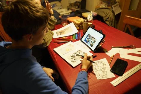 A man is drawing on a table with a tablet and a cell phone Stock Photos