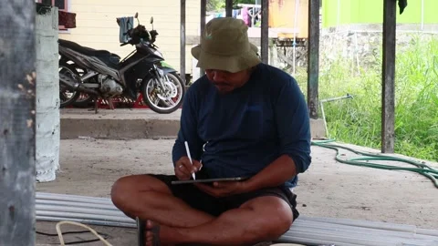 A man drawing using an iPad outdoors Vídeo Stock 323389119