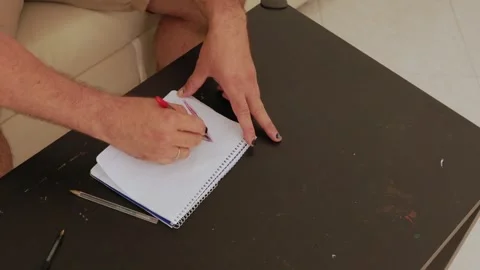 Man drawing zigzag lines on notepad with red pencil Stock Footage 316128160