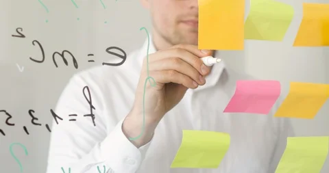 Man draws a graph on transparent screen near stickers with notes and formulas. Stock Footage 129900902