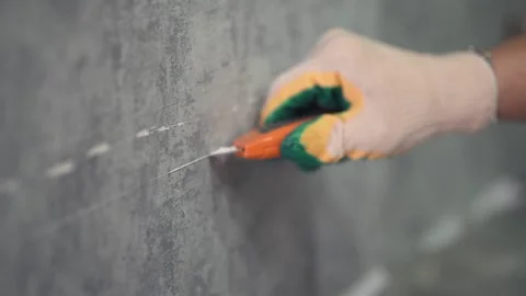 The man draws a line on the wall with a clerical knife. Stockbeeldmateriaal 147077286