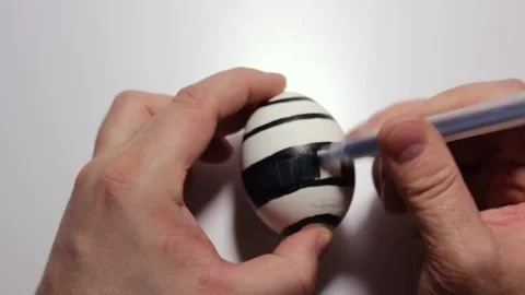 Μan draws pattern on easter egg with black felt tip pen Stock Footage 276740319