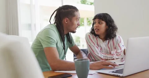 Man with dreadlocks and female partner using laptop together and talking in Stock Footage 337623253