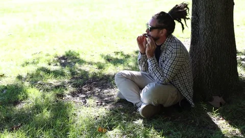 Man with Dreadlocks Ponytail in Sunglasses Playing Harmonica, Mouth Organ Stock Footage 291478444
