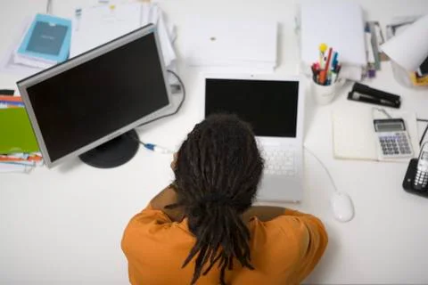 Man with dreadlocks working at desk, rear overhead view Stock Photos
