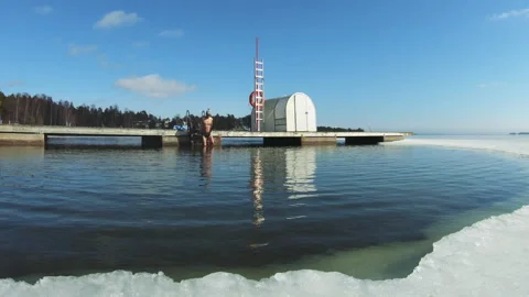 A man dreaming of a vacation floating on an inflatable flamingo in an ice hole Video stock 161039010