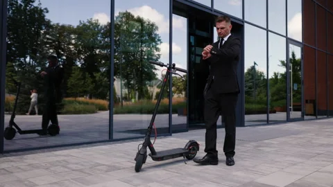 A man dressed in a black suit and tie exits a business center. The businessman Stock Footage 280613241
