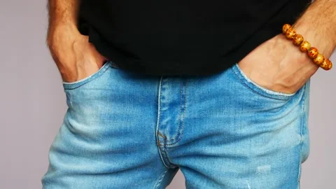 A man dressed in blue jeans stands with his hands folded on his belt close-up Stock Footage 142387662