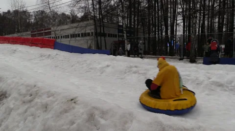 A man dressed as a chicken egg tosses and passes on a sled on a snowy hill. Stock Footage 35455537