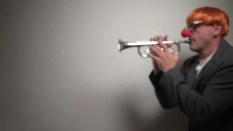 Man dressed as clown playing silver trumpet Stock Footage 323802930