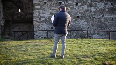 A man dressed in the down jacket pilots his drone near an ancient towe.. Stock Footage 71971293