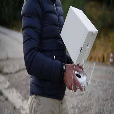 Man dressed in the down jacket watching his tablet while piloting the dro Video stock 69379122