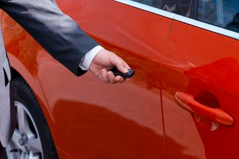 A man dressed in a gray suit opens or closes his car Stock Photos
