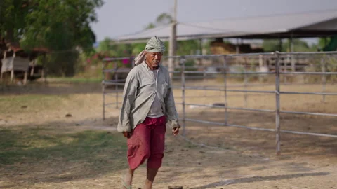 A man dressed in green and red walks through a ranch Stock Footage 265581689
