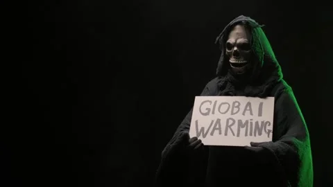 A man dressed as a grim reaper standing with a Global warming sign in his hands. Stock Footage 255478342