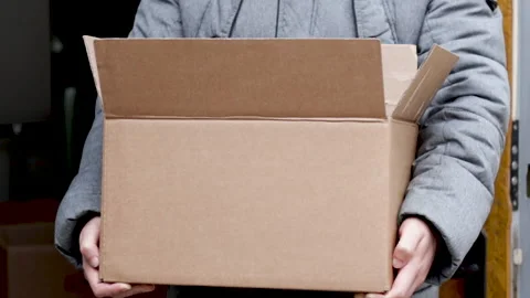 A man dressed is holding a brown delivery box in hands Vídeo Stock 166118997