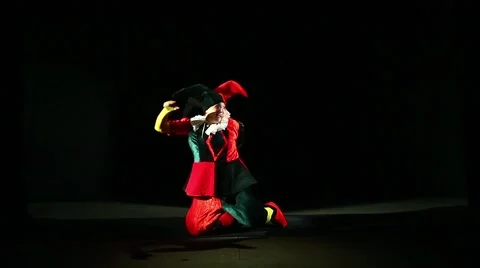A man dressed in a jester costume is playing on a black background Stock Footage 67628902
