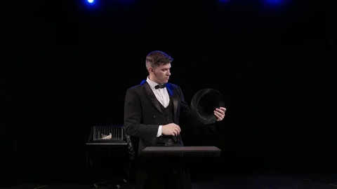 A man dressed as a magician pulling a rabbit from his hat Stock Footage