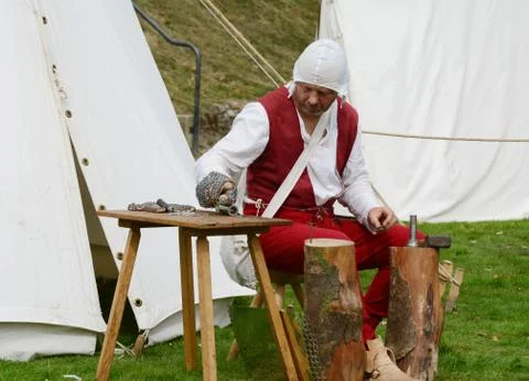 Man dressed in Medieval clothes making metal armour Stock Photos