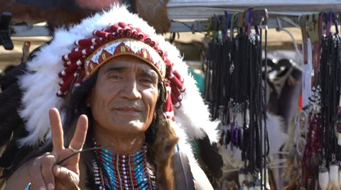 A man dressed as Native American Indians next to his shop souvenirs. Slow motion 스톡 동영상 63960268