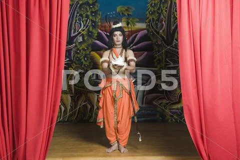 Man dressed-up as Rama holding a conch shell Stock Photos