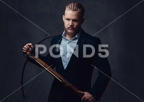 A man dressed in a suit holds crossbow. Stock Photos