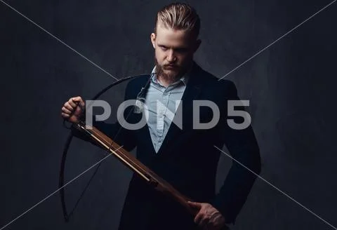 A man dressed in a suit holds crossbow. Stock Photos