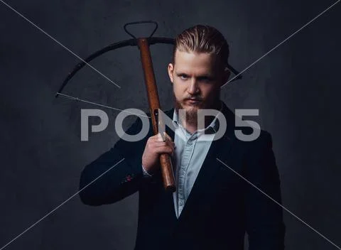 A man dressed in a suit holds crossbow. Stock Photos