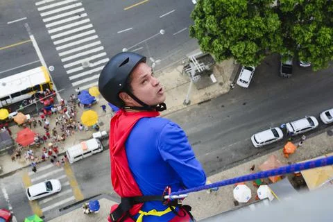 Man dressed as a superhero rappelling down from a tall building. Fotos de archivo