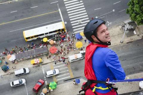 Man dressed as a superhero rappelling down from a tall building. Fotos de archivo