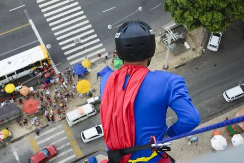 Man dressed as a superhero rappelling down from a tall building. Fotos de archivo