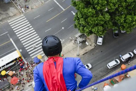 Man dressed as a superhero rappelling down from a tall building. Fotos de archivo