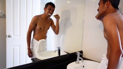 Man dressed in towel brushing the teeth in the morning. Stock Footage 72642473
