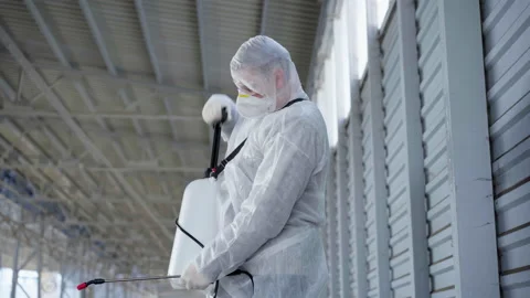 Man dressed white protective overalls spraying surface antibacterial sanitizer Stock-Footage 164325224