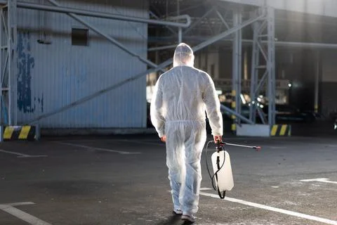 Man dressed white protective overalls spraying surface antibacterial sanitize Stock-Fotos